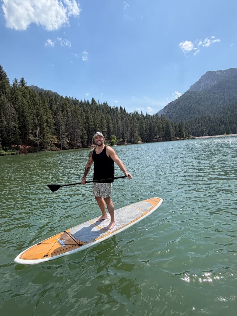Nick standing on a paddleboard on an alpine lake